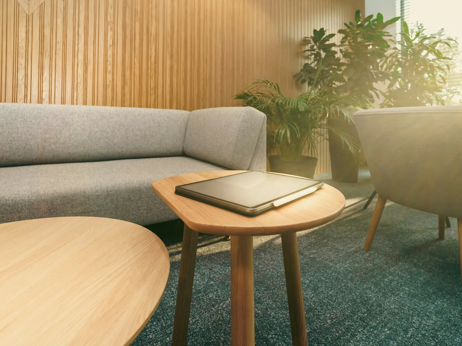Zithoek met een lichte bank en eiken bijzettafels voor een wand van houten lamellen en planten